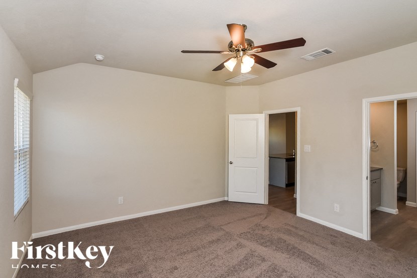 A spacious room with a ceiling fan and two doors.
