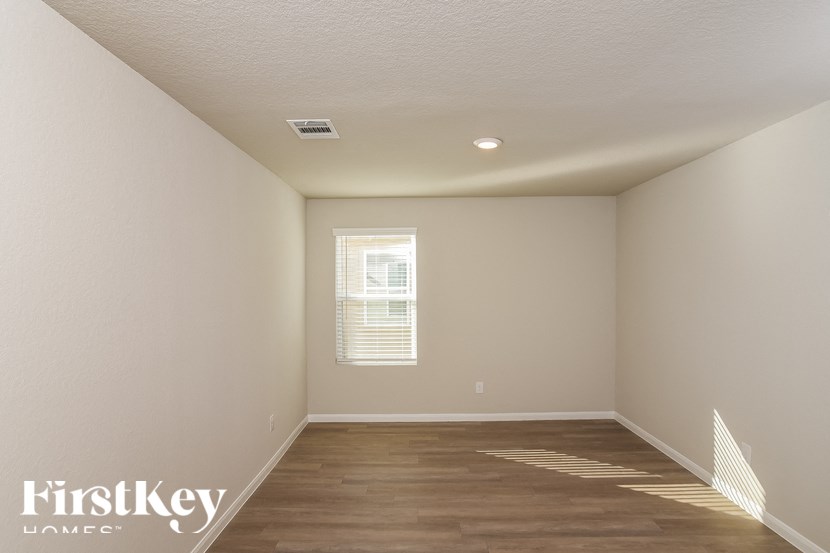 A room with wooden floors and a window with blinds.