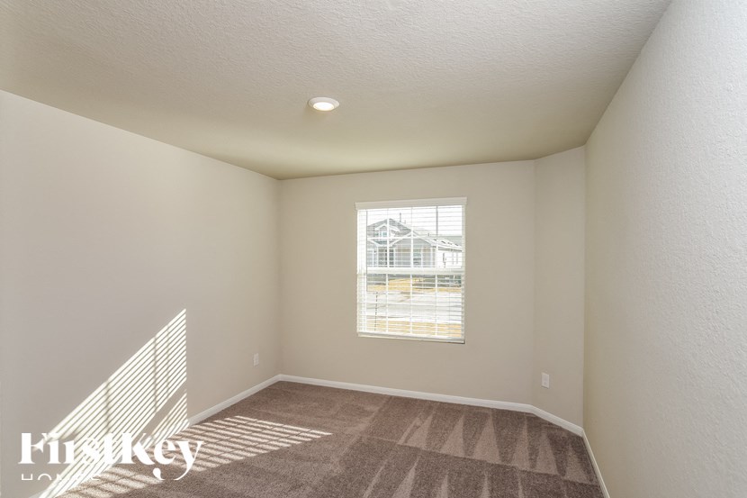 A room with a carpeted floor and a window showing a building outside.