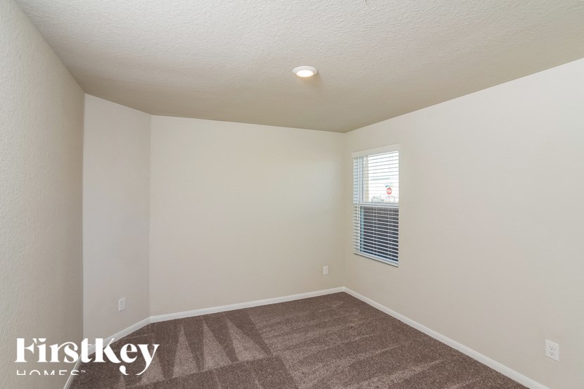A room with a carpeted floor and a window with blinds.