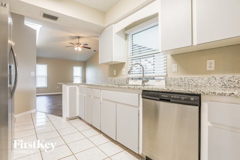 A kitchen with a stainless steel dishwasher and white cabinets.