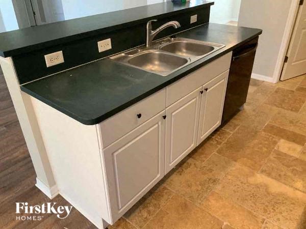 A kitchen with a sink and a black countertop.