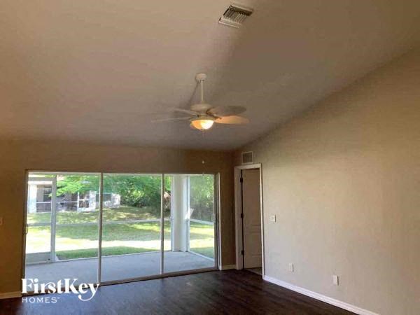 A room with a ceiling fan and sliding glass doors.