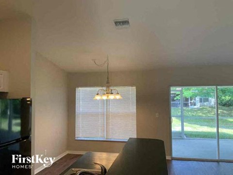 A kitchen with a black counter top and a window with blinds.