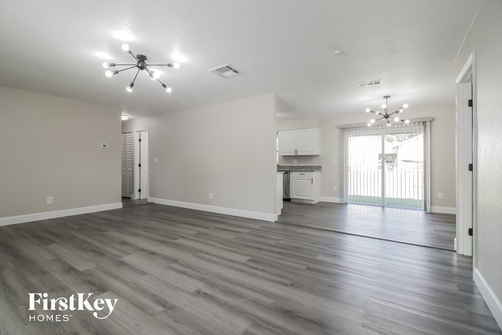 A spacious room with a ceiling fan and a kitchen area in the background.