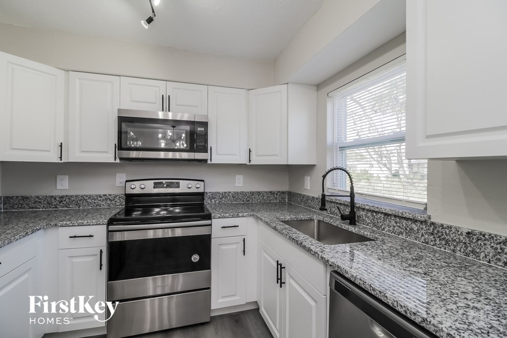 A kitchen with a stove top oven and a microwave above it.