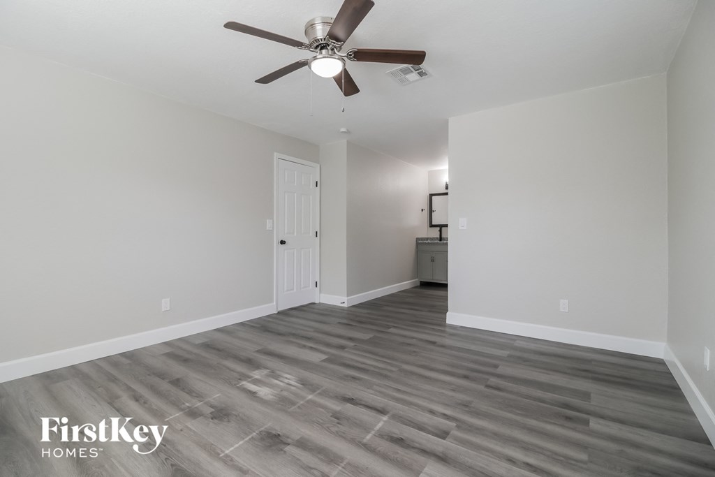 A room with a ceiling fan and wooden flooring.