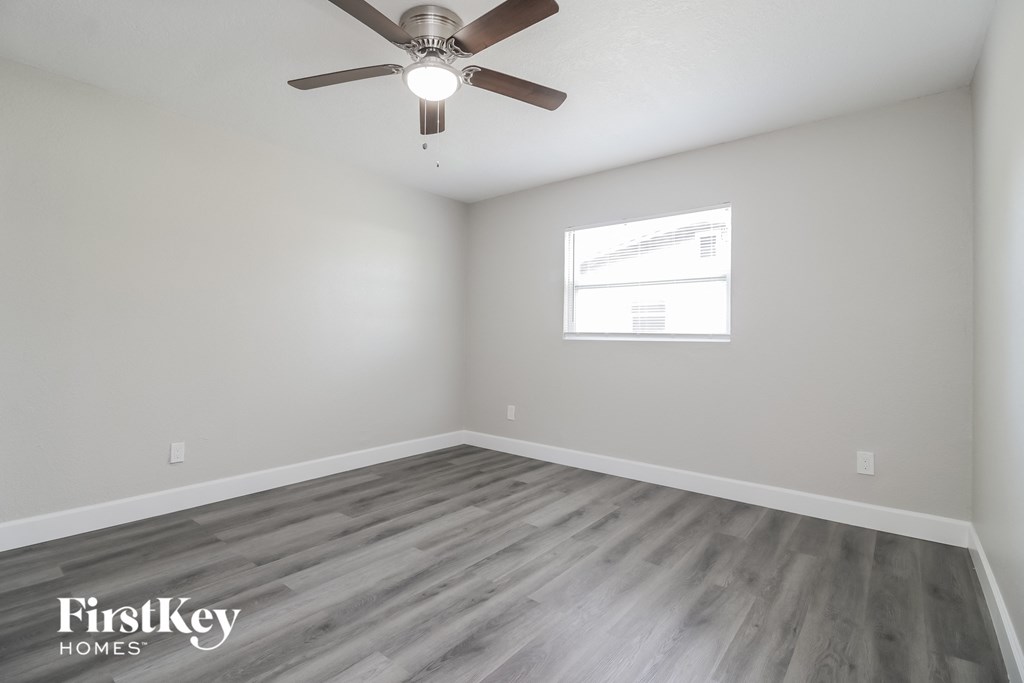 A room with a ceiling fan and wooden flooring.