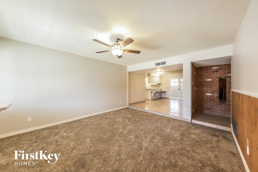 an empty living room with a ceiling fan and a bathroom