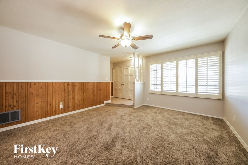 an empty living room with a ceiling fan and a window
