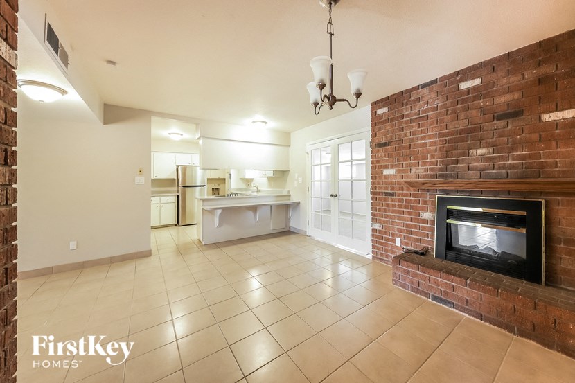 a large living room with a brick fireplace and tiled floors