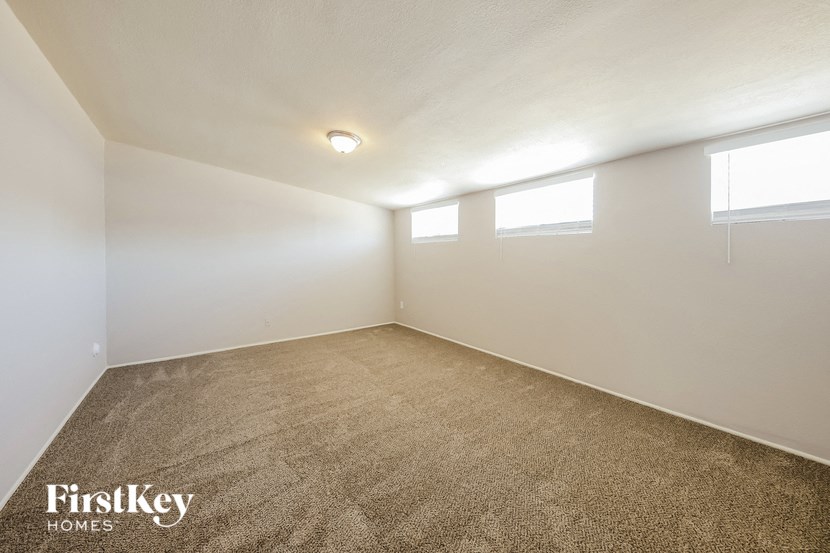 an empty room with a carpeted floor and three windows
