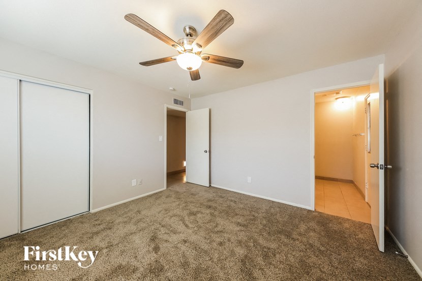 an empty living room with a ceiling fan and a closet