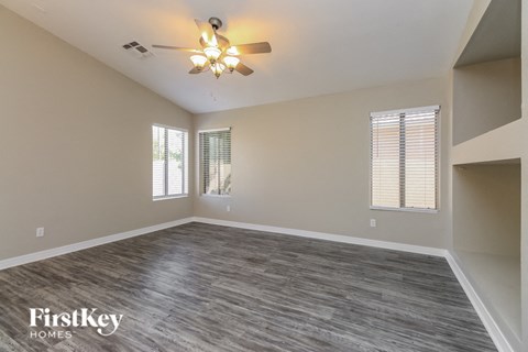 an empty living room with a ceiling fan and window