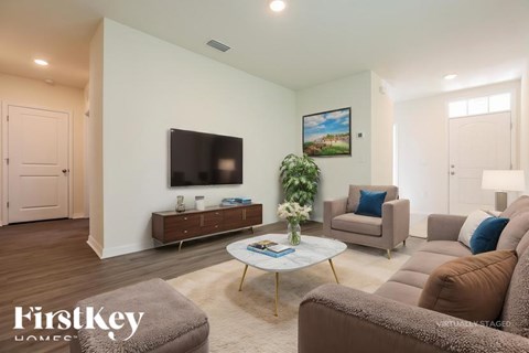 A living room with a brown couch, a coffee table, and a flat screen TV mounted on the wall.