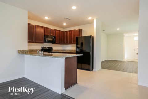 A kitchen with brown cabinets and a black refrigerator.