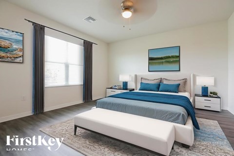 A bedroom with a large bed, a painting on the wall, and a window with curtains.