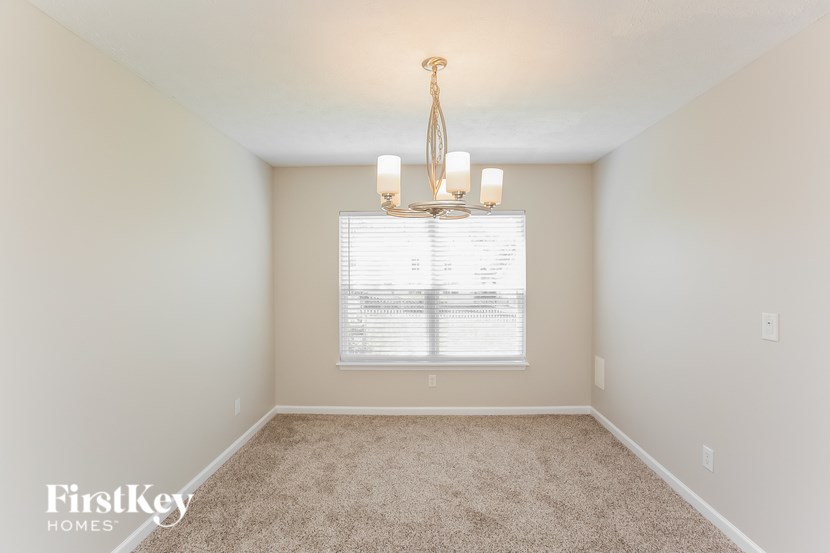 A well-lit room with a chandelier and a window with blinds.