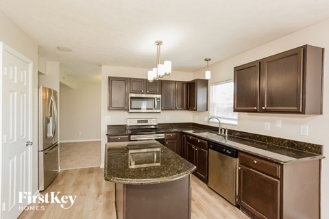 A kitchen with brown cabinets and a granite countertop.