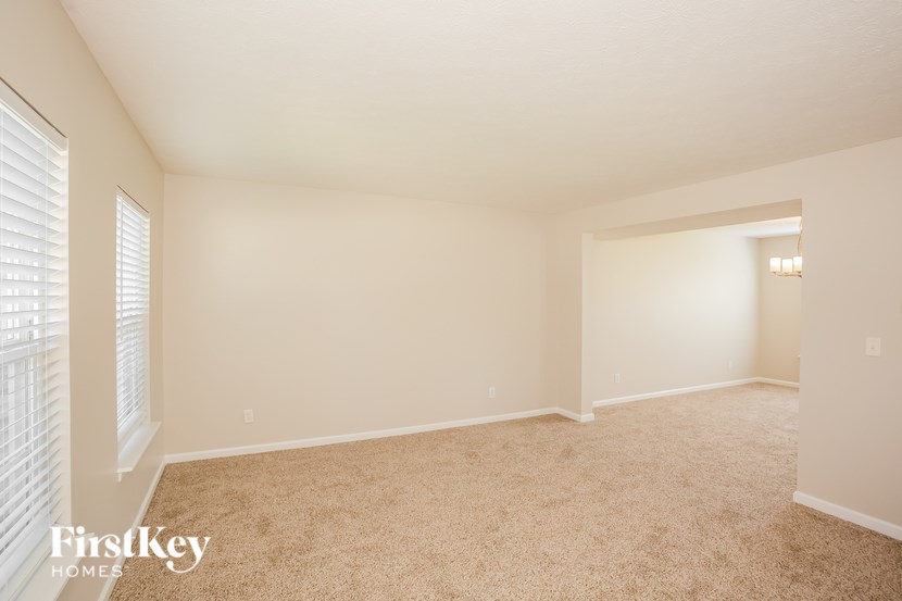 A room with a carpeted floor and a window with blinds.