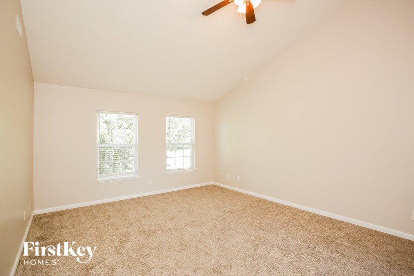 A room with a carpeted floor and a ceiling fan.