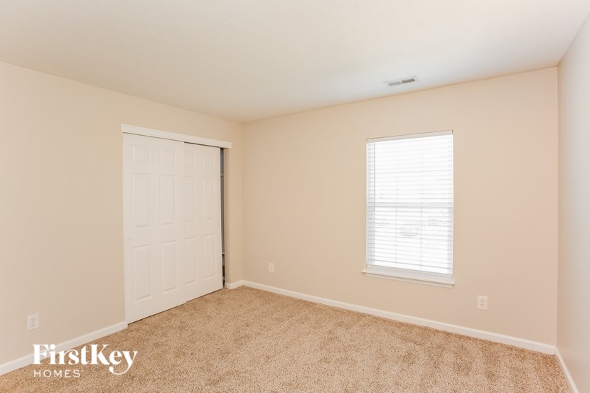 A room with a white door and a window with blinds.