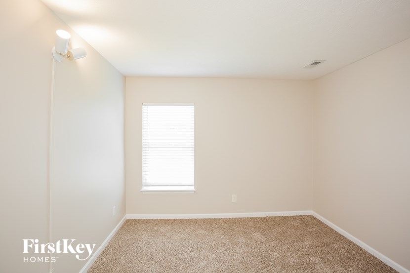 A room with a window and a carpeted floor.