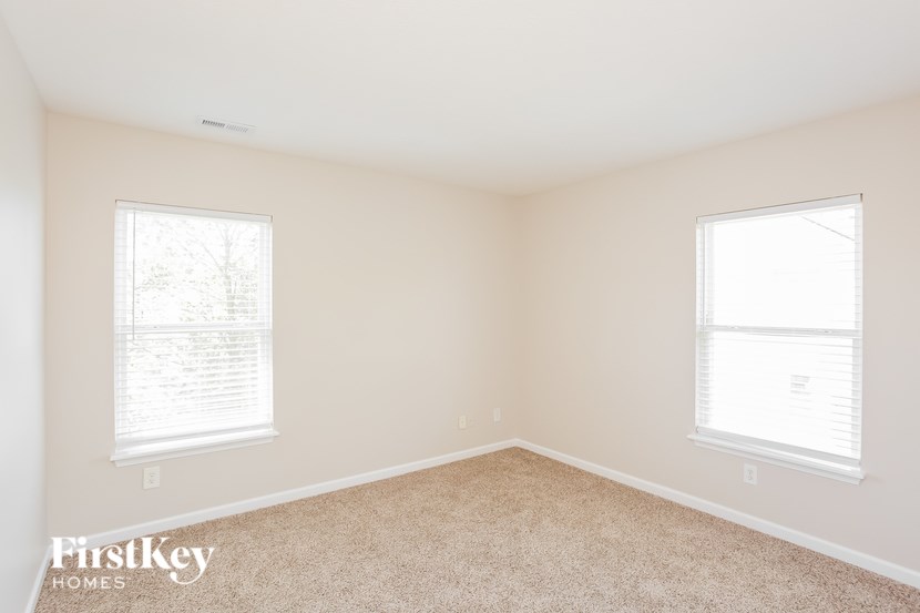 A room with two windows and a carpeted floor.
