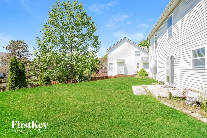 A white house with a green lawn and a tree in front of it.