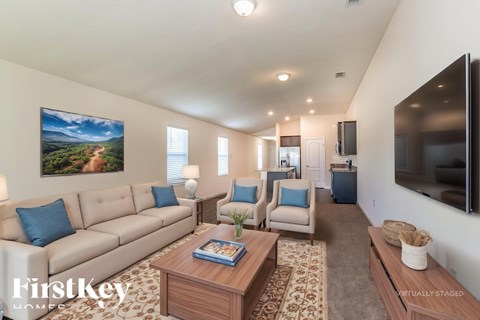 A living room with a couch, chairs, and a painting on the wall.