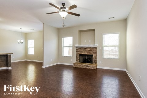 A spacious room with a fireplace and a ceiling fan.