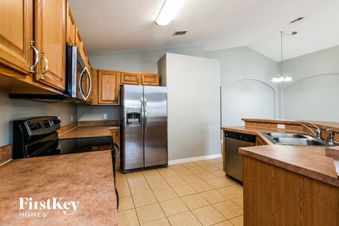 A kitchen with wooden cabinets and a stainless steel refrigerator.