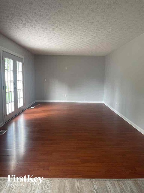 an empty living room with wood floors and white walls