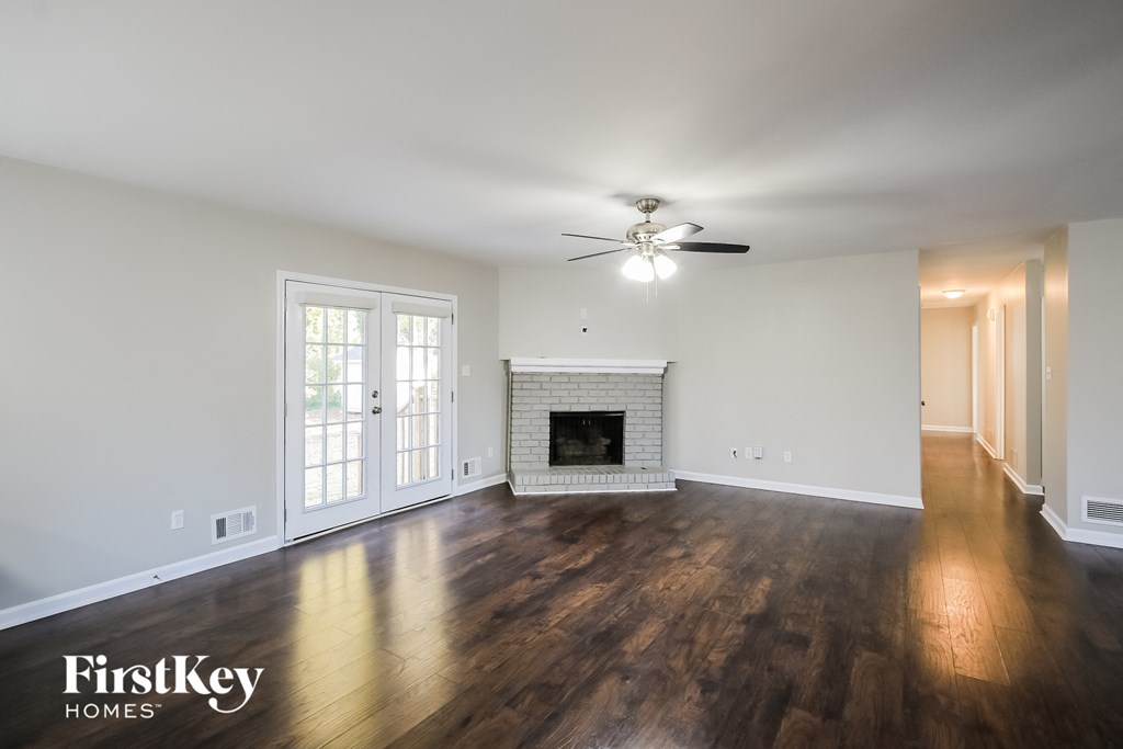 an empty living room with a fireplace and a ceiling fan