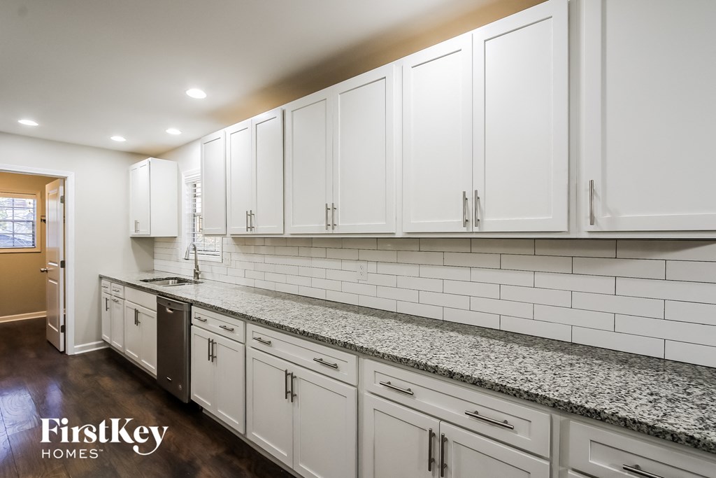 a white kitchen with granite counter tops and white cabinets