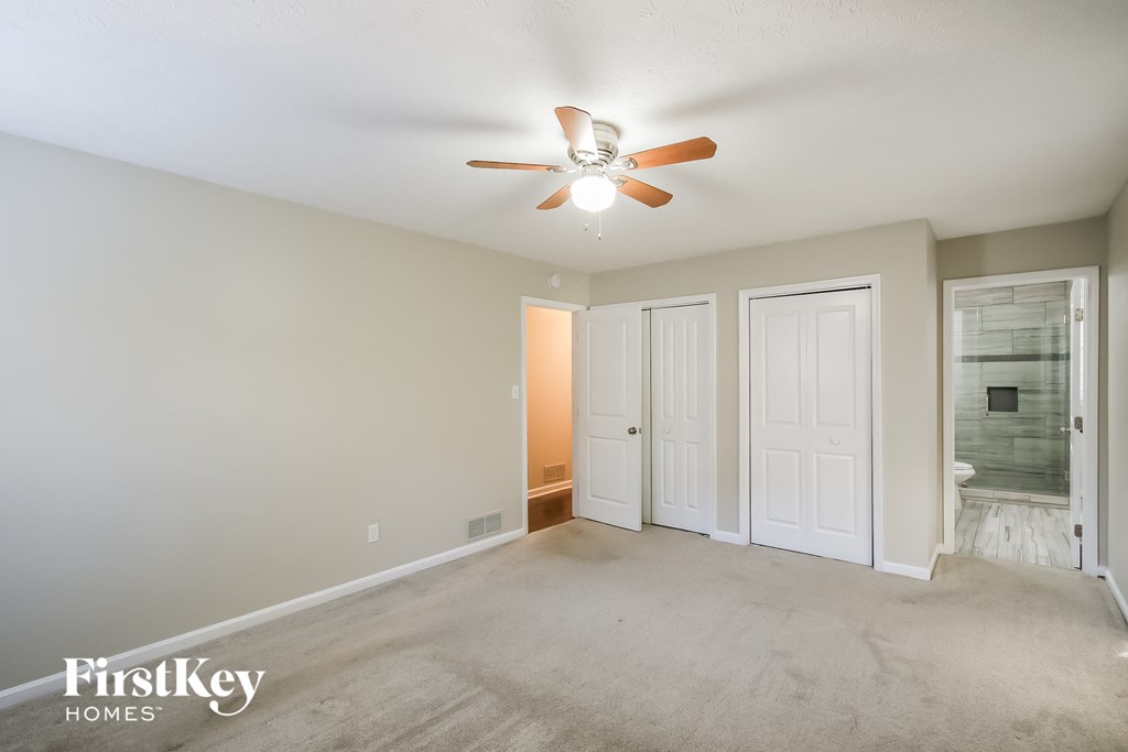 a living room with a ceiling fan and a door to a bathroom