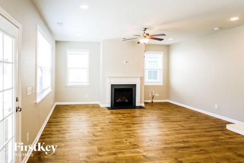 A spacious living room with a fireplace and wooden floors.