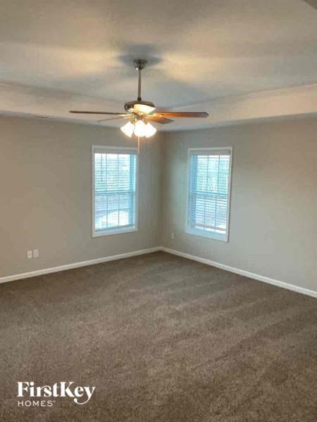 an empty room with a ceiling fan and two windows