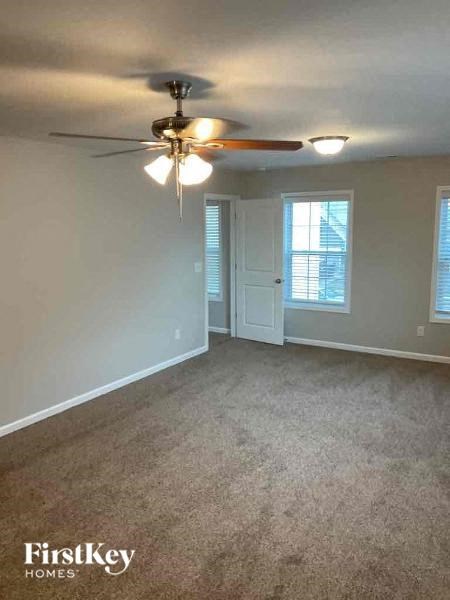 an empty living room with a ceiling fan and a door