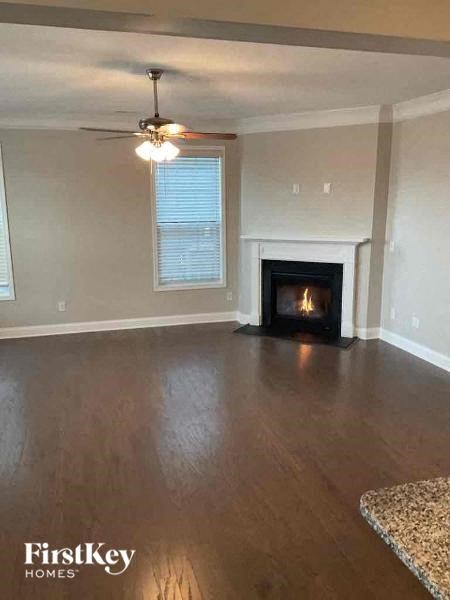an empty living room with a fireplace and a ceiling fan