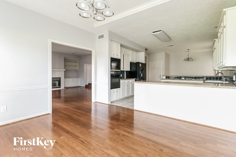 A kitchen with white cabinets and a wooden floor.