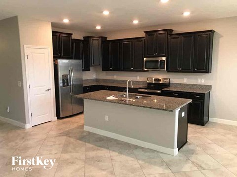 A kitchen with a granite countertop and a stainless steel refrigerator.