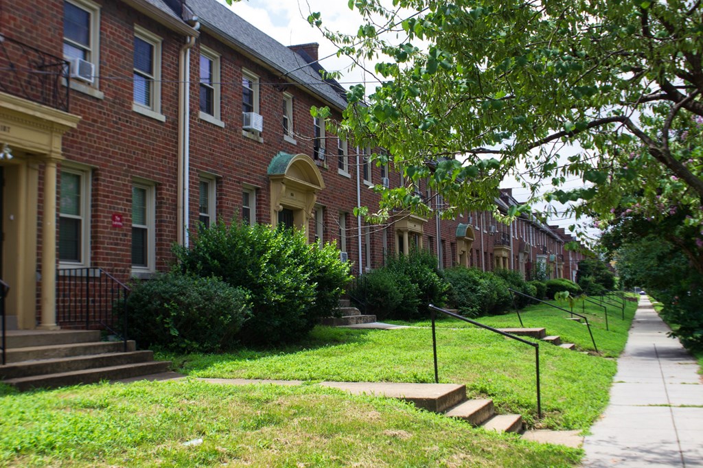 A row of red brick houses with green lawns in front.