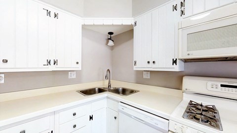 a white kitchen with white cabinets and a sink