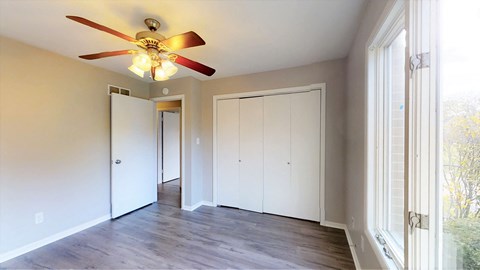 an empty living room with a ceiling fan and white closets