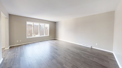 an empty living room with wood floors and a window