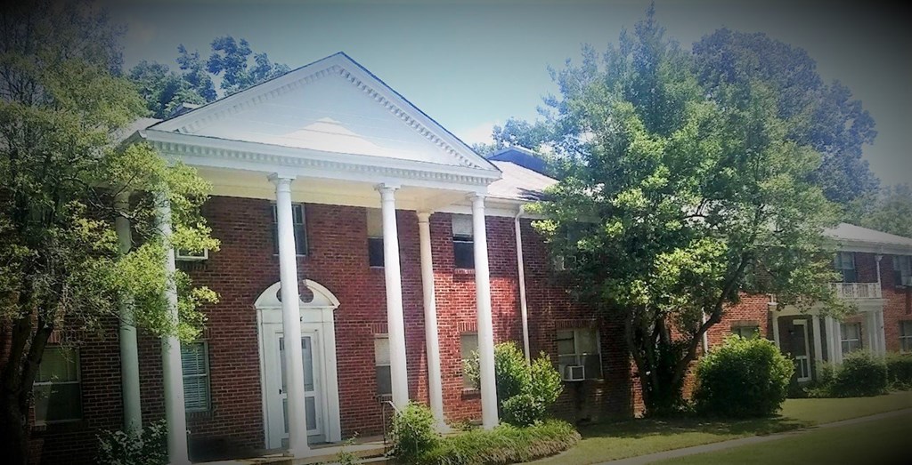 a red brick house with white columns    and trees