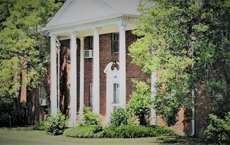 the front of a brick house with columns and a white porch
