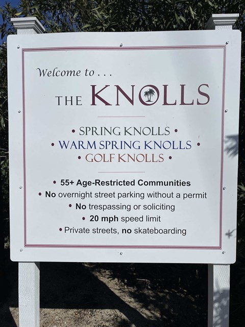 a sign for spring knolls on the side of a road