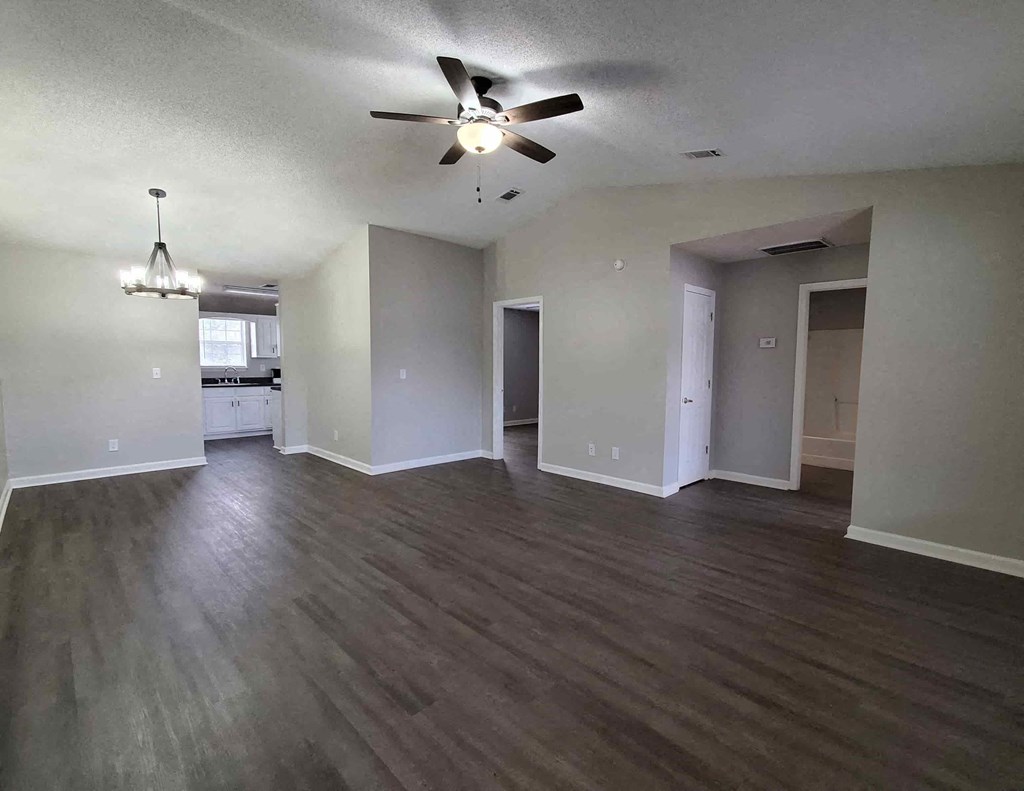 an empty living room and kitchen with a ceiling fan